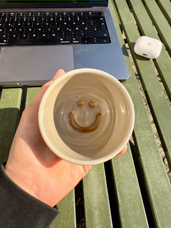 The bottom of a coffee cup with coffee stain shaped like a smiley :-)